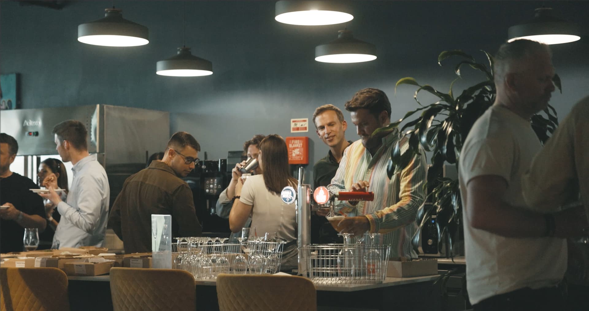 People pouring drinks and mingling at an office party 