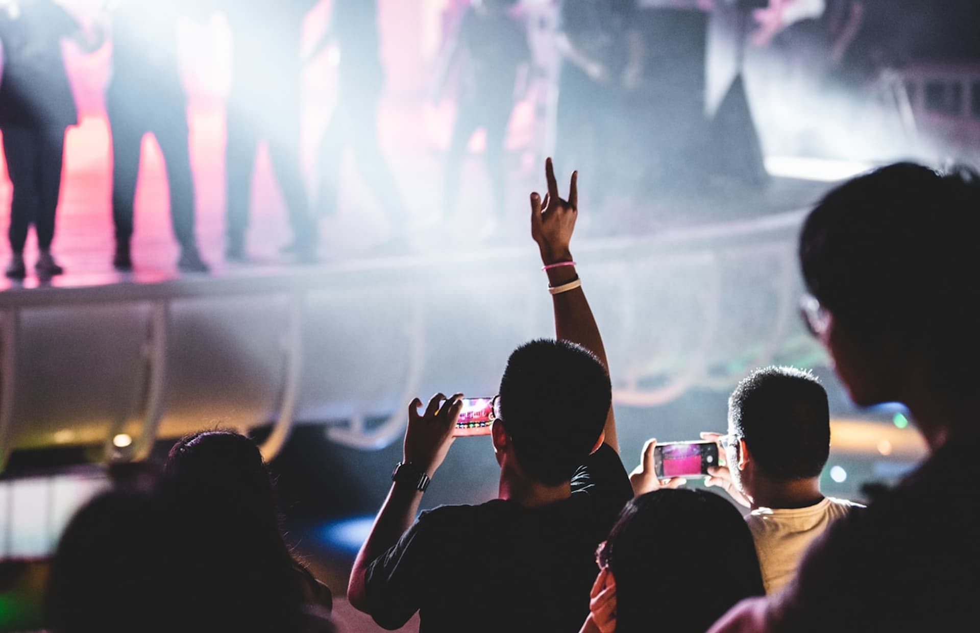 a person at a concert recording the act on his phone whilst simultaneously dancing