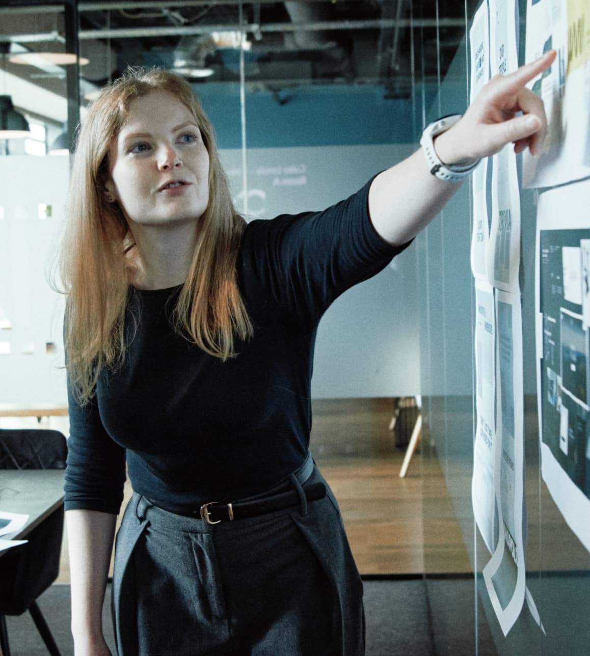 Designer pointing at a creative concept displayed on a board, explaining key elements to teammates.